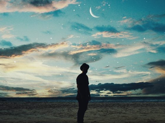 man standing under the moon and clouds