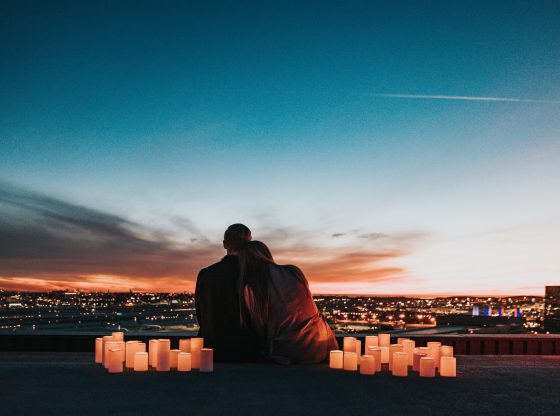 couple sitting on roof with lanterns