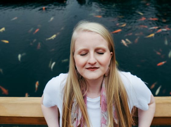 peaceful woman smiles by koi pond