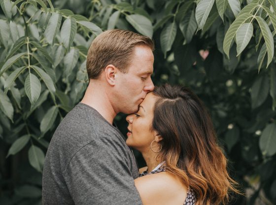 man kissing woman on forehead