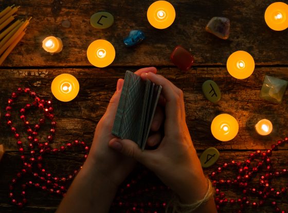 hands holding tarot cards by candlelight