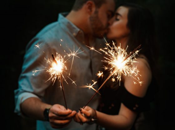 couple holding sparklers and kissing