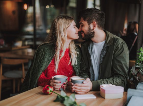 Beautiful young couple touching noses and smiling at cafe