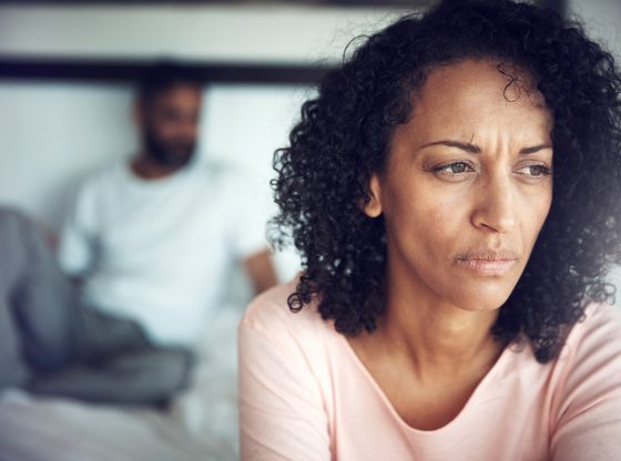 Shot of a mature woman looking upset with her husband in the background