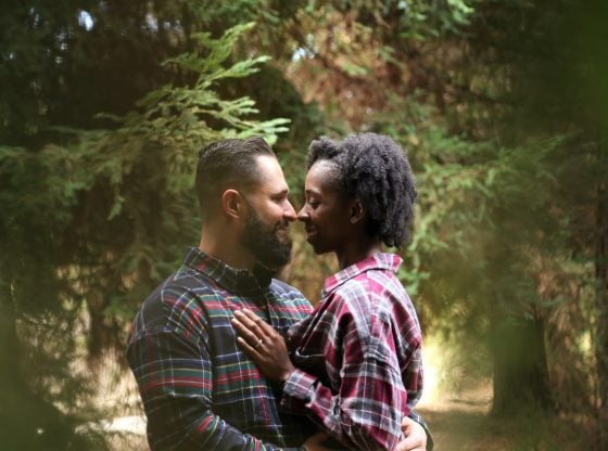 mixed couple hugging in the woods