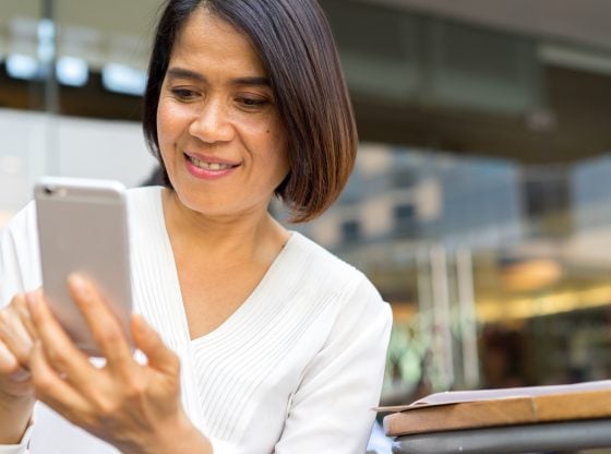 Happy Asian woman texting on smartphone