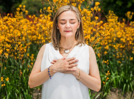 Mature woman meditating in garden of yellow flowers