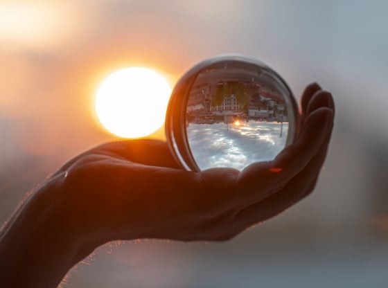 Crystal ball in hand reflecting sunset