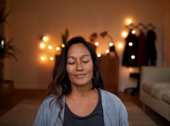 Serene mature woman smiling while meditating at home